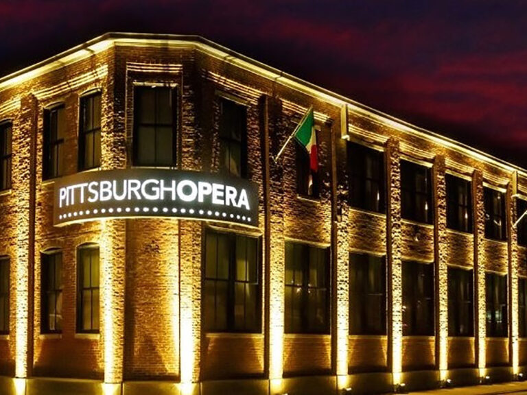 Nighttime photo of Pittsburgh Opera building aglow in the Strip District