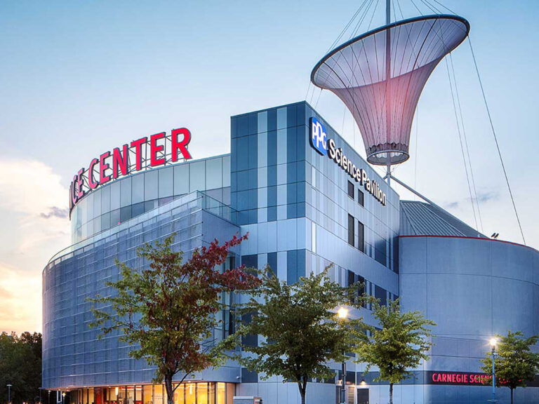 Exterior of the Carnegie Science Center with glowing red sign at dusk