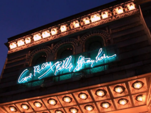 Nighttime photo of the blue neon sign on the exterior of the Kelly Strayhorn Theater